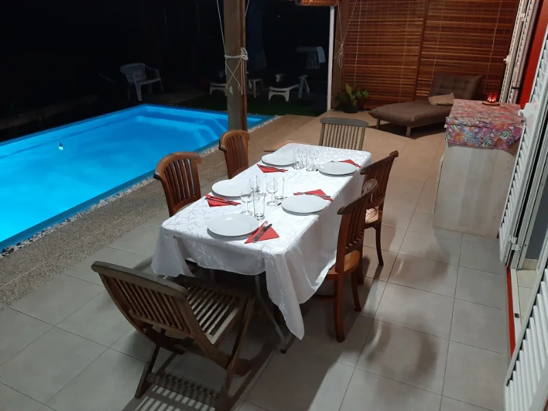 La table d'hôtes dressée le soir sur la terrasse, au bord de la piscine éclairée